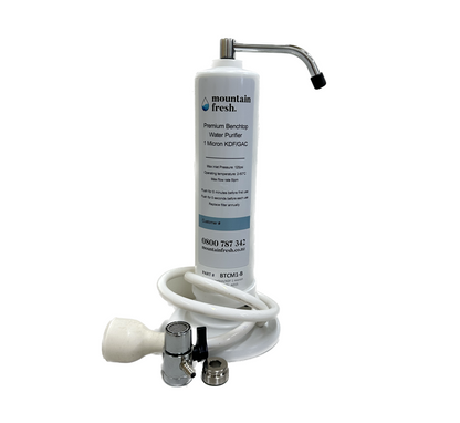 Mountain Fresh Portable Benchtop Water Purifier, compact black and silver unit with tap attachment, placed on a kitchen countertop.
